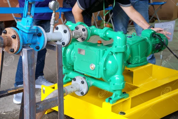 Cận cảnh bơm màng thân xanh với hộp giảm tốc và động cơ, đặt trên khung đế vàng